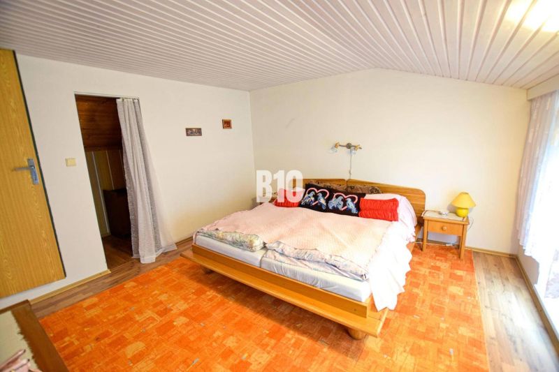 Schlafzimmer in einer Hütte mit Bett, Vorhängen und orangem Teppich.