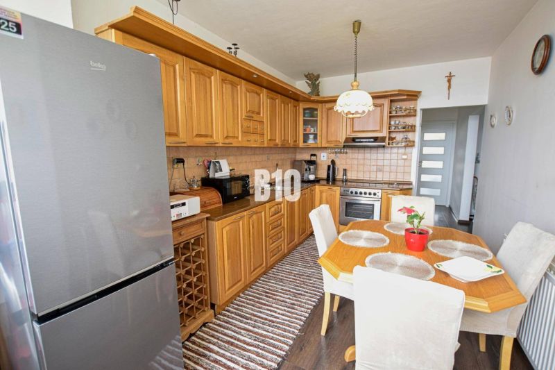 Küche in einer 3-Zimmer-Wohnung mit einer Eckküche und einem Boden in Holzoptik.
