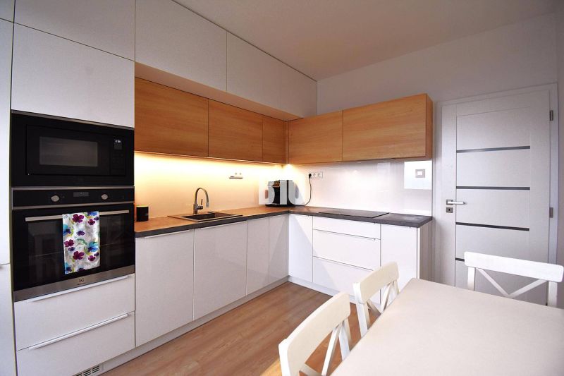 Küche einer 3-Zimmer-Wohnung mit Holzelementen und Geräten, einschließlich Backofen und Kochfeld.