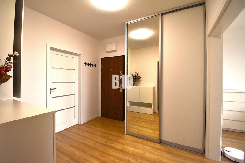 Eingangsbereich mit weißem Schrank und Spiegel, Boden mit Holzdekor, 3-Zimmer-Wohnung.
