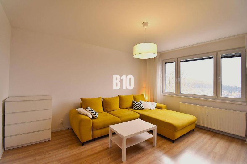 Wohnzimmer einer 3-Zimmer-Wohnung mit gelbem Sofa und Boden in Holzoptik.