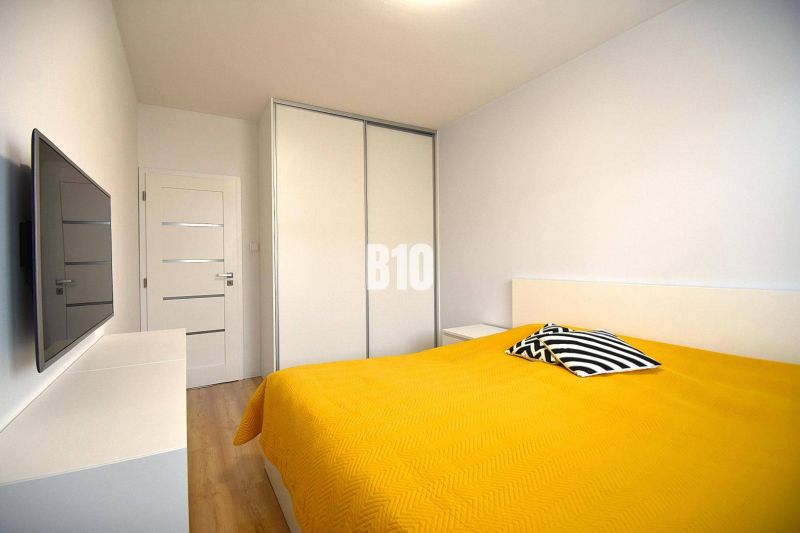 Schlafzimmer in einer 3-Zimmer-Wohnung mit Holzboden und gelber Bettdecke.