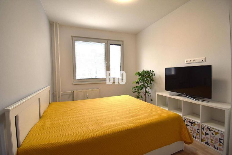 Schlafzimmer in einer 3-Zimmer-Wohnung mit Bett, Fernseher und Holzboden.