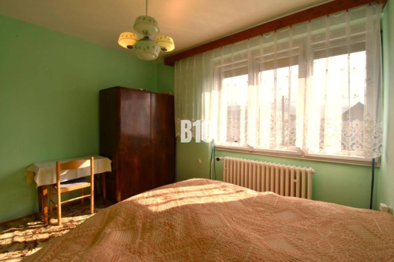 Schlafzimmer im Einfamilienhaus mit Fenster, Vorhängen, Schrank und Tisch.