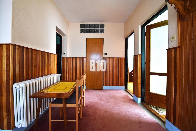 Der Flur in einem Einfamilienhaus mit Holzverkleidung, Tisch und Stuhl.