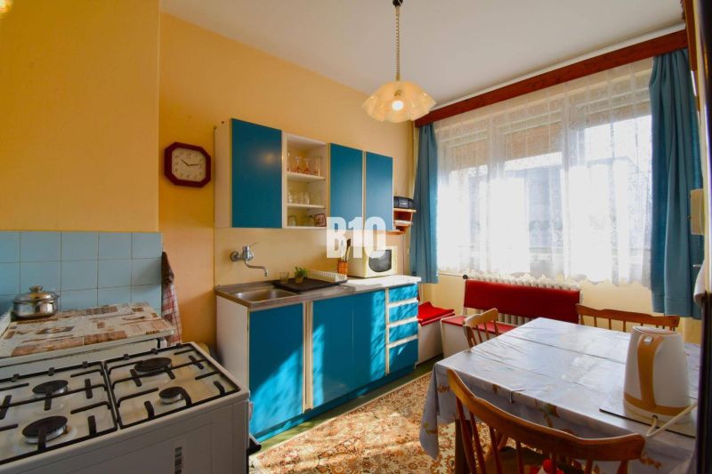 Küche in einem Einfamilienhaus mit blauer Küchenzeile, Gasherd und Esstisch.