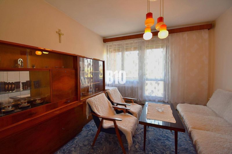Wohnzimmer in einem Einfamilienhaus mit Retro-Möbeln und Vorhängen am Fenster.