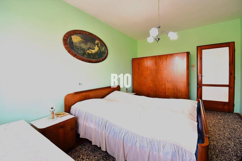 Ein Schlafzimmer in einem Einfamilienhaus mit massiven Holzmöbeln und einem dekorativen Bild an der Wand.