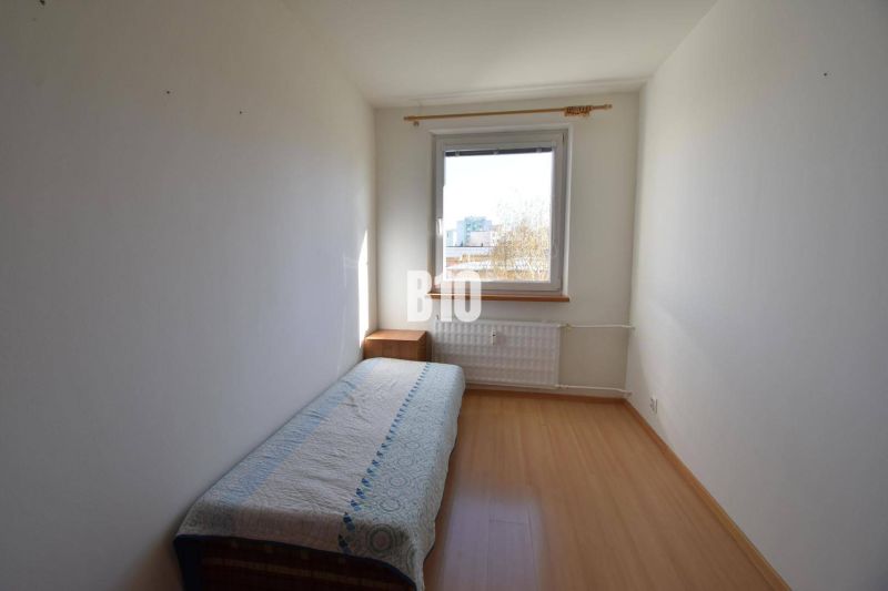 Ein Zimmer mit einem Einzelbett, einem Nachttisch und einem Boden mit Holzdekor in einer Wohnung mit 5 oder mehr Zimmern.