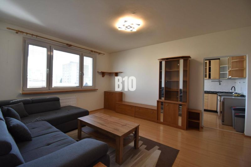 Wohnzimmer mit Holzboden, grauem Sofa und Holzmöbeln.