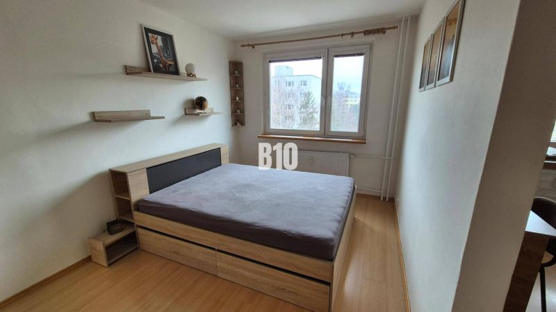 Einfaches Schlafzimmer mit Bett und Holzregalen in einer Wohnung mit 5 oder mehr Zimmern.