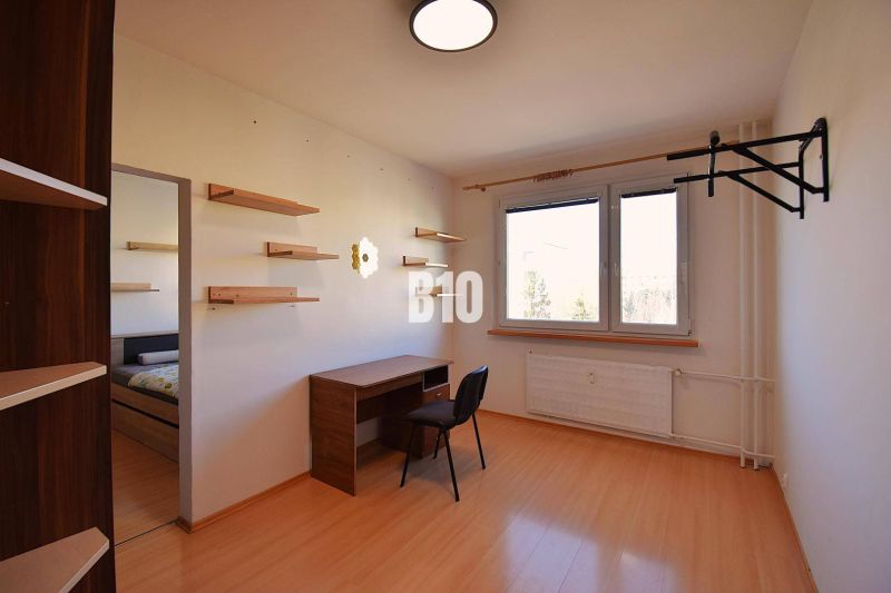 Ein Arbeitszimmer mit Regalen, einem Tisch und einem Boden mit Holzdekor in einer Wohnung mit 5 oder mehr Zimmern.