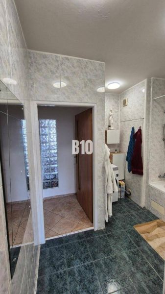 Badezimmer mit Duschkabine, weißen Fliesen und dunklem Boden in einer Wohnung mit 5 oder mehr Zimmern.