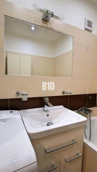 Badezimmer in einer 4-Zimmer-Wohnung mit Waschbecken, Spiegel und Waschmaschine.
