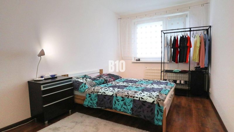 Helles Schlafzimmer in einer 4-Zimmer-Wohnung mit Bett und Boden in Holzoptik.