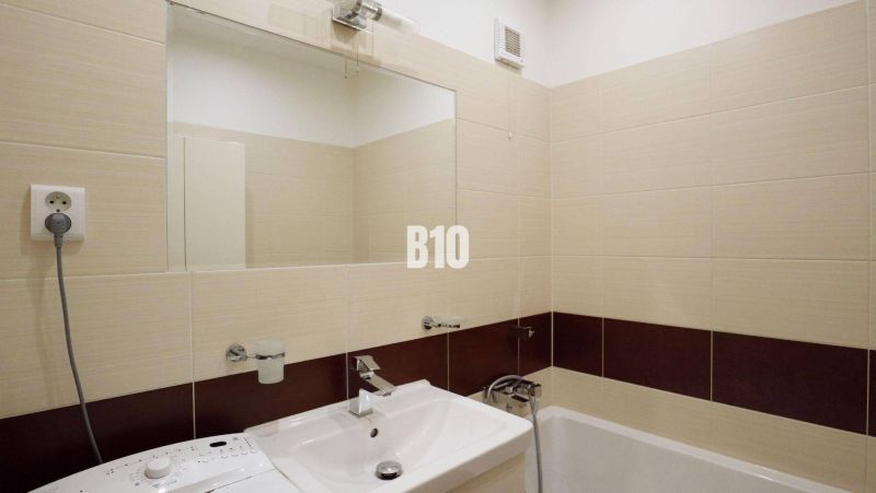 Badezimmer mit Dusche und Waschbecken in einer 4-Zimmer-Wohnung, cremefarbene Fliesen.