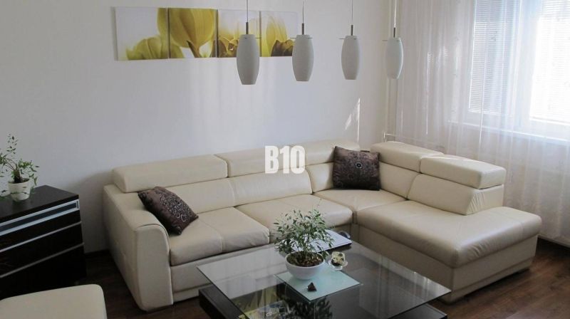 Elegantes Wohnzimmer in einer 4-Zimmer-Wohnung mit cremefarbenem Sofa und Boden in Holzoptik.