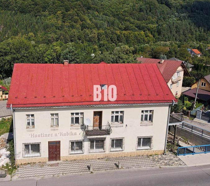 Ein Gebäude in Belej mit rotem Dach, umgeben von Grün und einer Straße im Vordergrund.