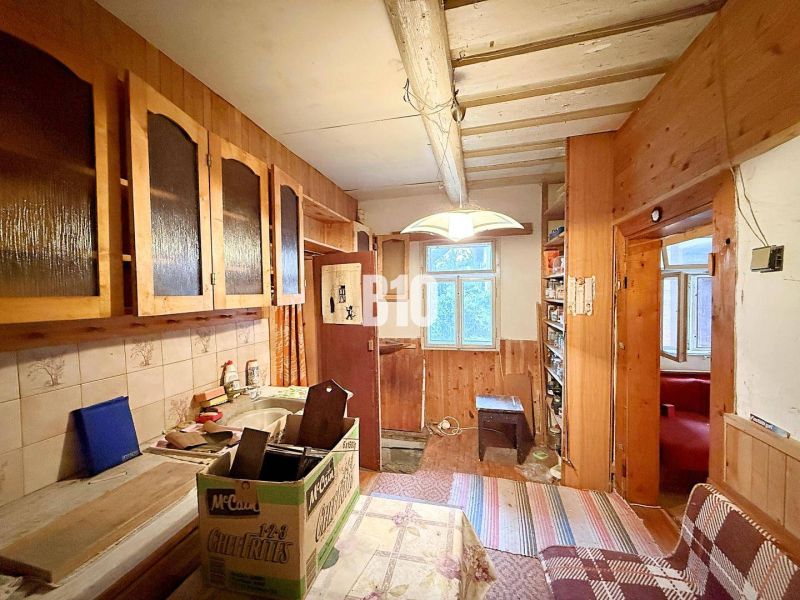 Küche eines Einfamilienhauses mit Holzschränken und gefliester Wand.