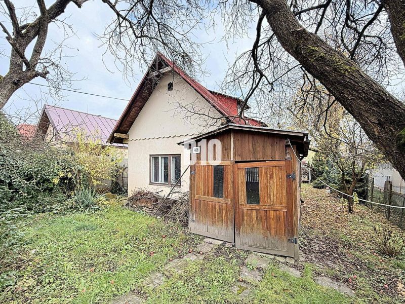 Ein Einfamilienhaus in Kotešová mit einem Holzunterstand und einem Garten im Herbst.