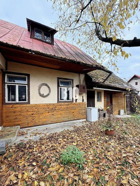 Ein Einfamilienhaus in Kotešová mit alter Holzverkleidung und fallendem Laub im Garten.