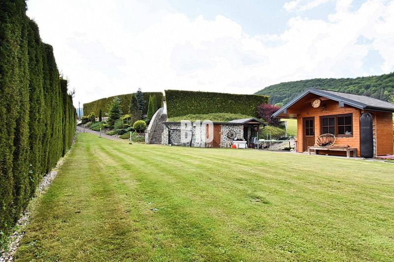 Ein gepflegter Rasen bei der Villa in Súľov-Hradná mit einem Holzhaus und einer Hecke.