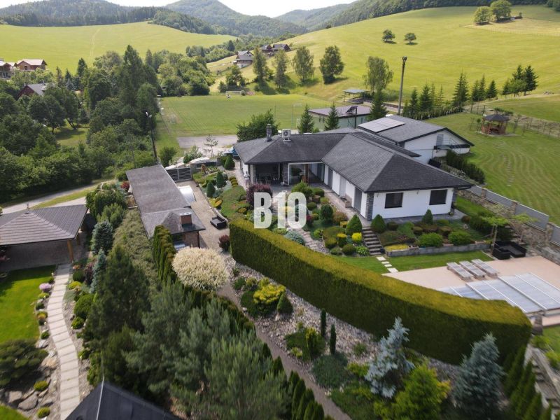 Eine Villa in Súľov-Hradná, umgeben von einem schönen Garten und hügeliger Landschaft.