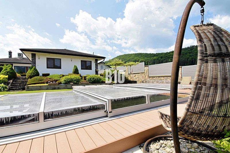 Eine Villa in Súľov-Hradná, ein gepflegter Garten mit Pool und eine bequeme Außensitzgelegenheit.