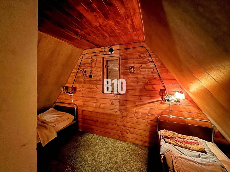 Rustikales Interieur einer Hütte mit zwei Betten und Holzverkleidung an den Wänden.