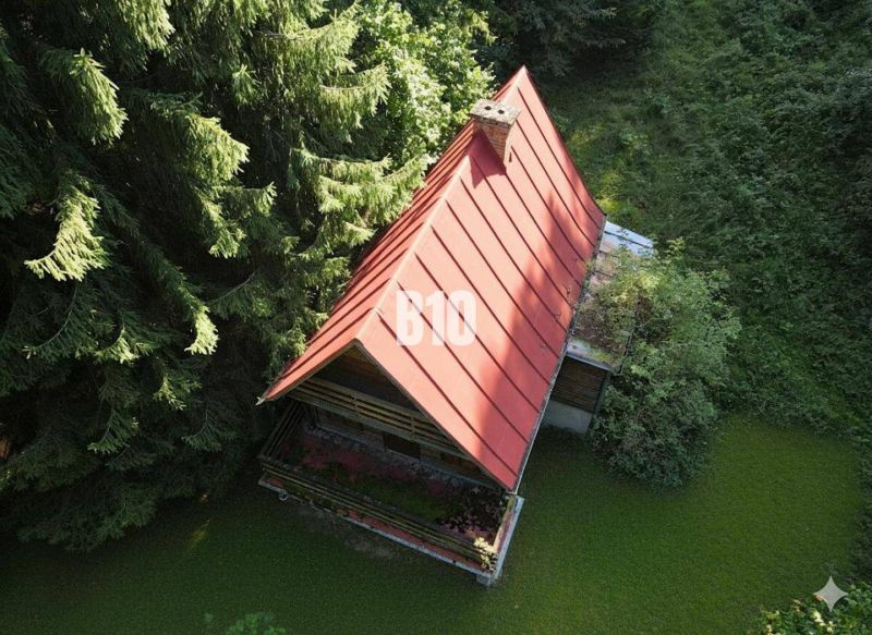 Eine Hütte in Kunerad mit einem schrägen Dach, umgeben von dichtem Baumbestand.