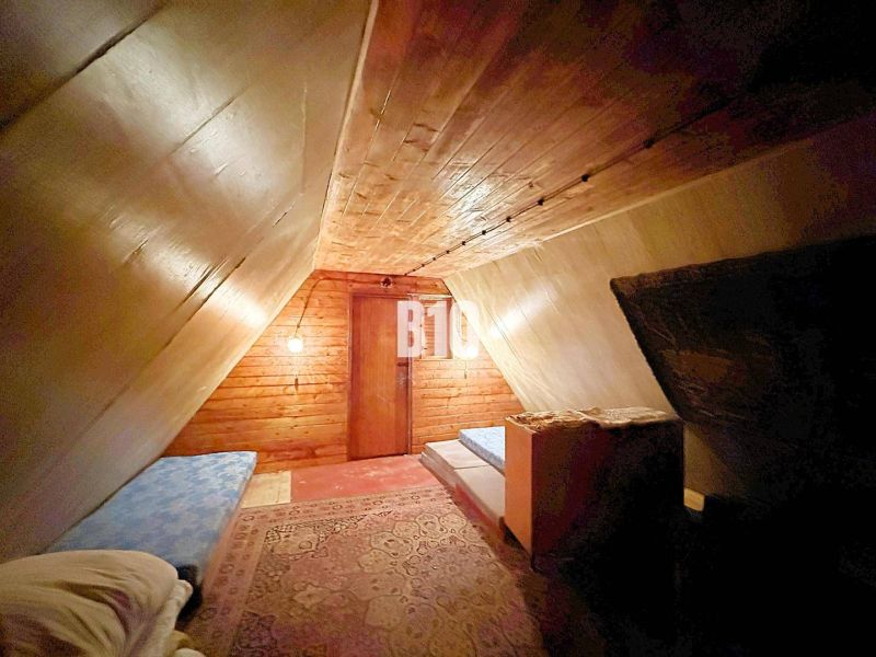 Das Dachgeschoss der Hütte mit schräger Decke, Betten und Boden in Holzoptik.