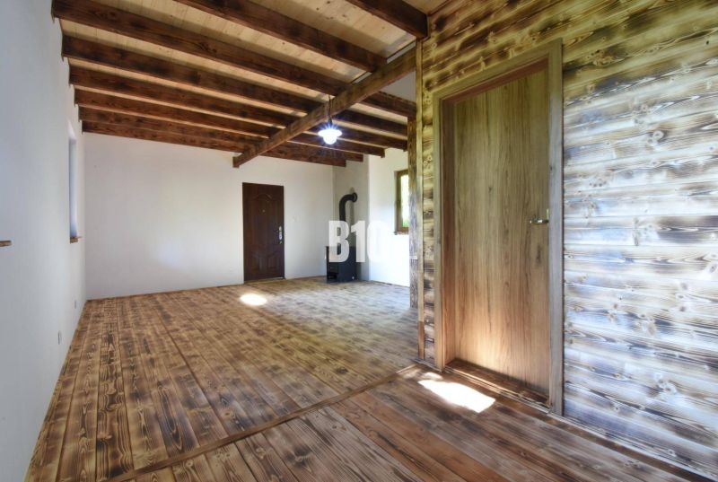 Interieur einer Hütte mit Holzbalken, Holzboden und einem Ofen zum Heizen.