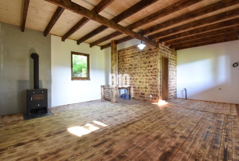 Das Innere der Hütte mit Holzbalken und Kamin, Holzboden und weißen Wänden.