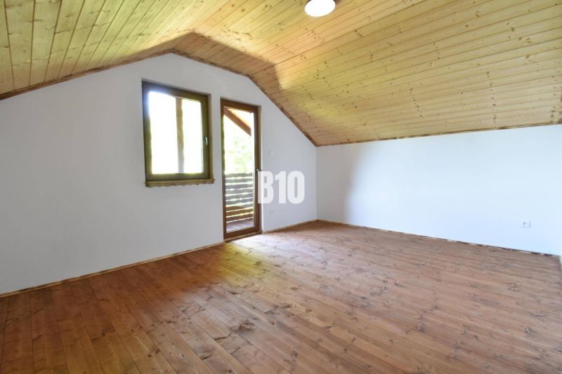 Dachbodenräume der Hütte mit Holzboden und -decke, Fenster und Tür zur Terrasse.