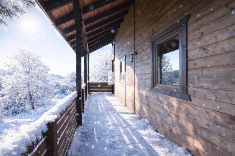 Die verschneite Terrasse einer Holzhütte in Bytča mit Blick auf die Winterlandschaft.