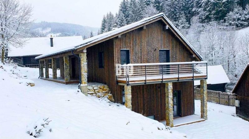 Eine verschneite Hütte in Horná Mariková, umgeben von Wald und schöner Winterlandschaft.