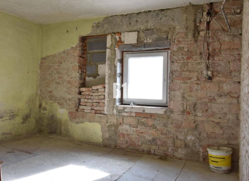 Ein Zimmer in einem Einfamilienhaus mit Ziegelwänden und einem Eimer auf dem Boden.