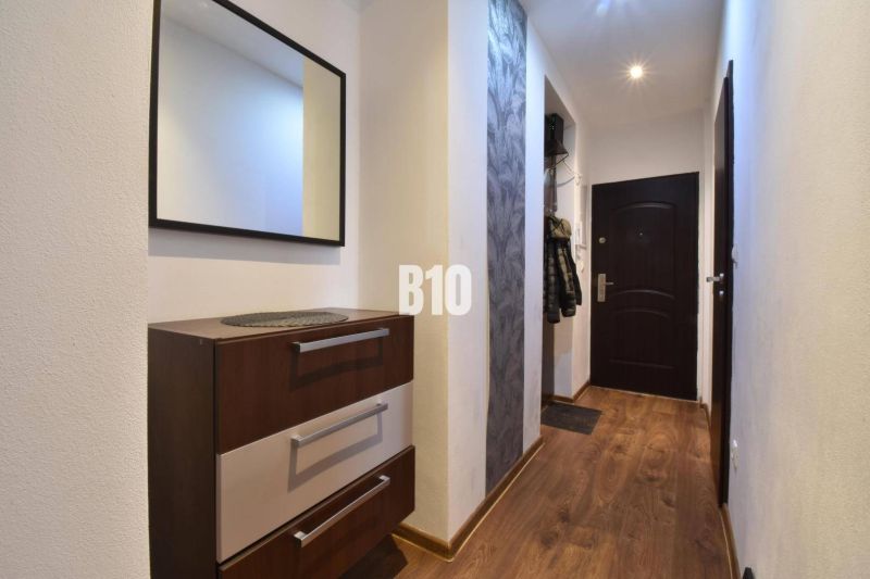 Flur mit Spiegel, Kommode und Boden mit Holzdekor in einer 3-Zimmer-Wohnung.
