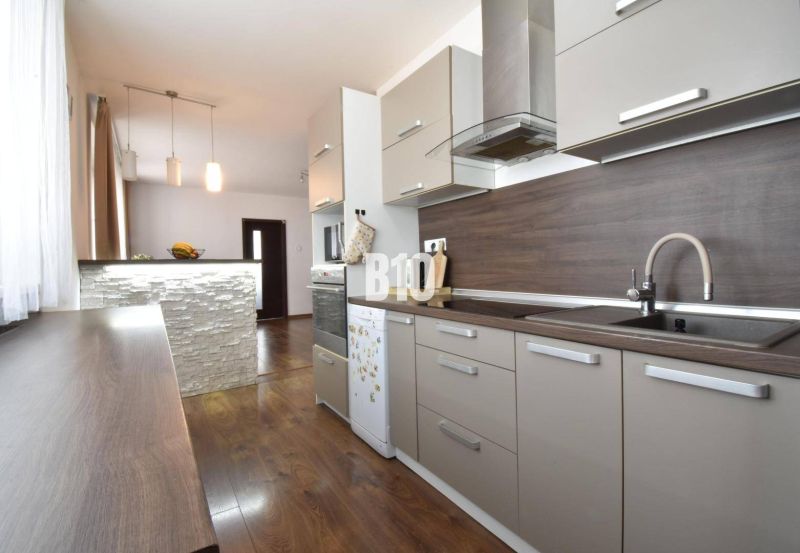 Küche in einer 3-Zimmer-Wohnung mit einer Küchenzeile und einem Boden in Holzoptik.