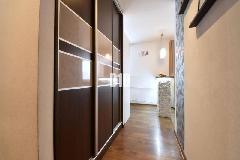 Der Flur in einer 3-Zimmer-Wohnung mit einem Holzboden und einem Einbauschrank.