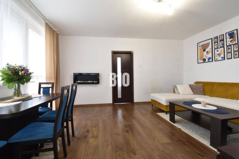 Wohnzimmer in einer 3-Zimmer-Wohnung mit Holzboden, Sofa und Esstisch.