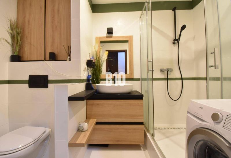 Badezimmer in einer 3-Zimmer-Wohnung mit Holzdekor und Duschkabine.