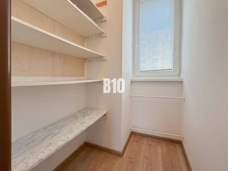 Kleiner Raum in einer Ferienwohnung mit Regalen und Fenster, Boden mit Holzdekor.