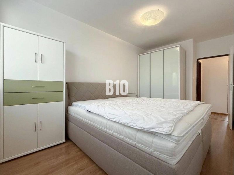 Helles Zimmer in einer Ferienwohnung mit Bett, Kleiderschränken und Holzboden.