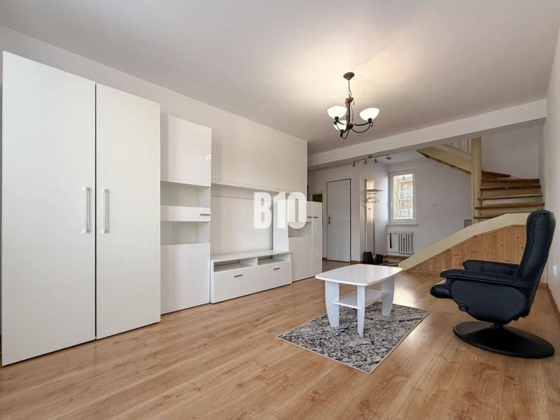 Wohnzimmer in einer Ferienwohnung mit weißen Möbeln und einem Boden in Holzoptik.