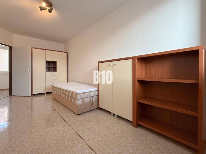 Helles Zimmer in einer Ferienwohnung mit Bett, Schrank und Regalsystem.