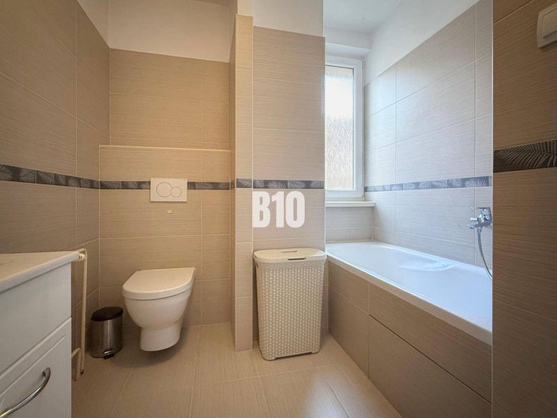 Badezimmer in einer Ferienwohnung mit Badewanne, Toilette und modernen Fliesen.