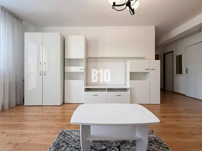 Innenraum einer Ferienwohnung mit weißen Möbeln und Boden in Holzoptik.
