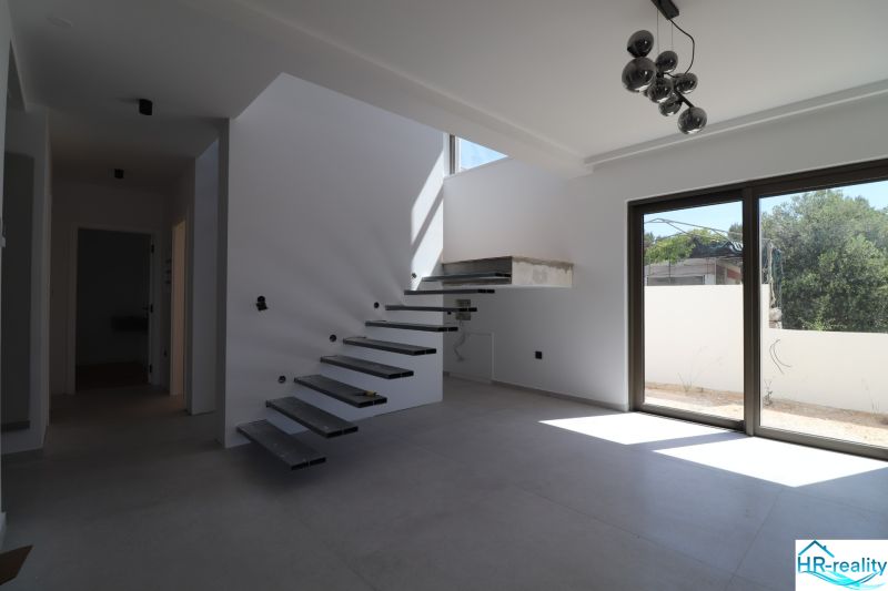 Eine Treppe mit offenen Stufen im Inneren der Villa und einem großen Fenster.