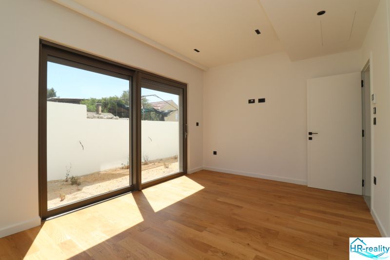 Zimmer in der Villa mit Holzboden und großem Fenster zur Terrasse.